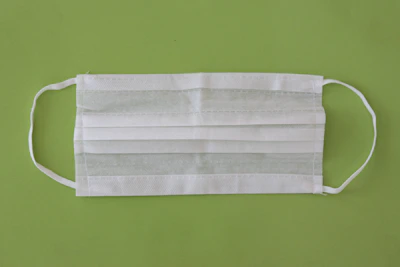 Disposable medical supplies like gloves and masks displayed on a light green background.