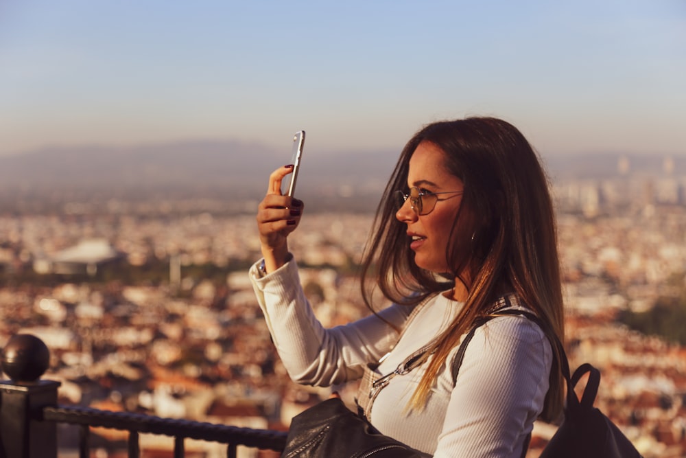woman in white long sleeve shirt holding smartphone