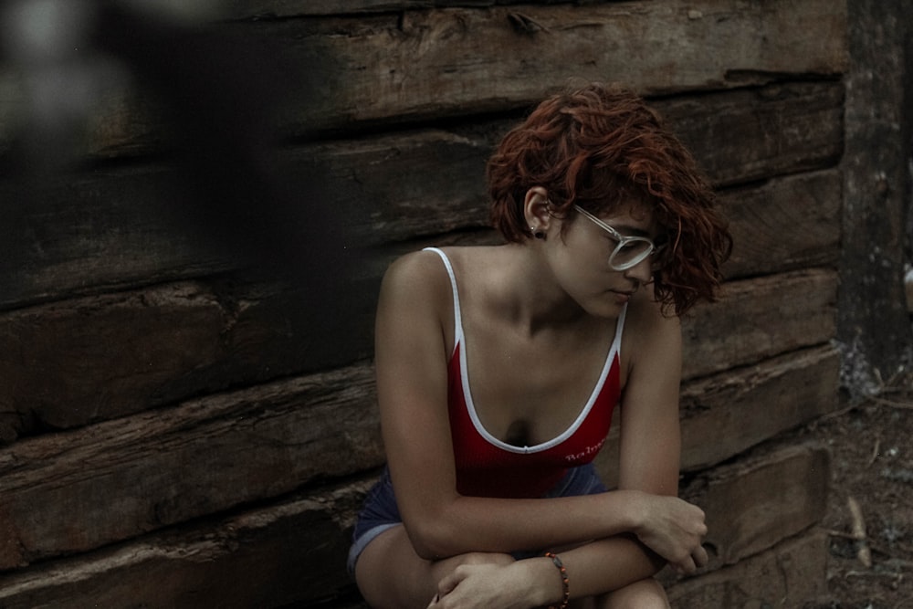 woman in blue tank top sitting on brown wooden floor