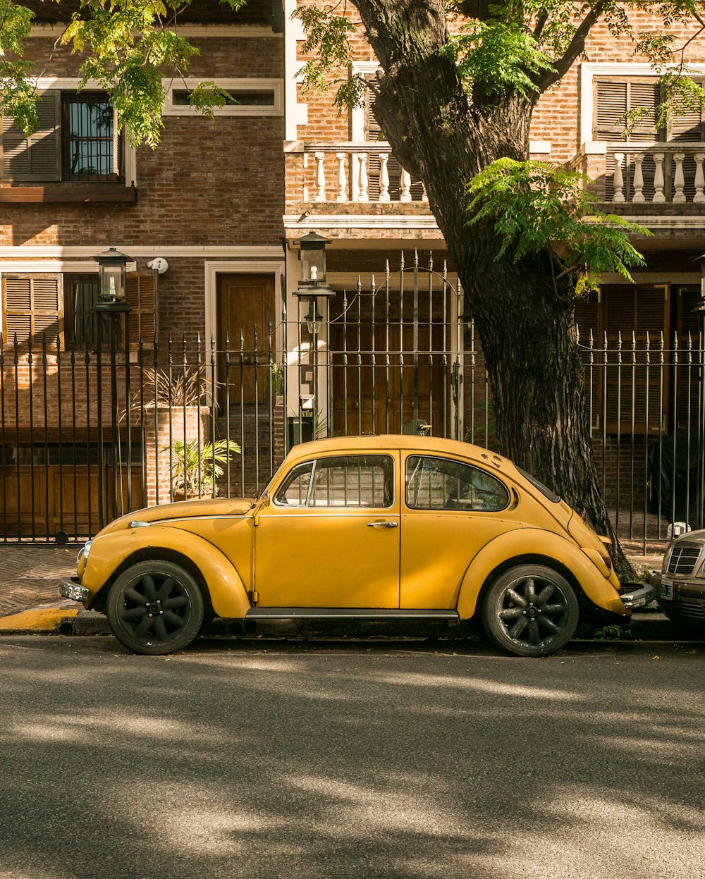 Volkswagen Beetle amarillo aparcado junto a un edificio de ladrillos marrones