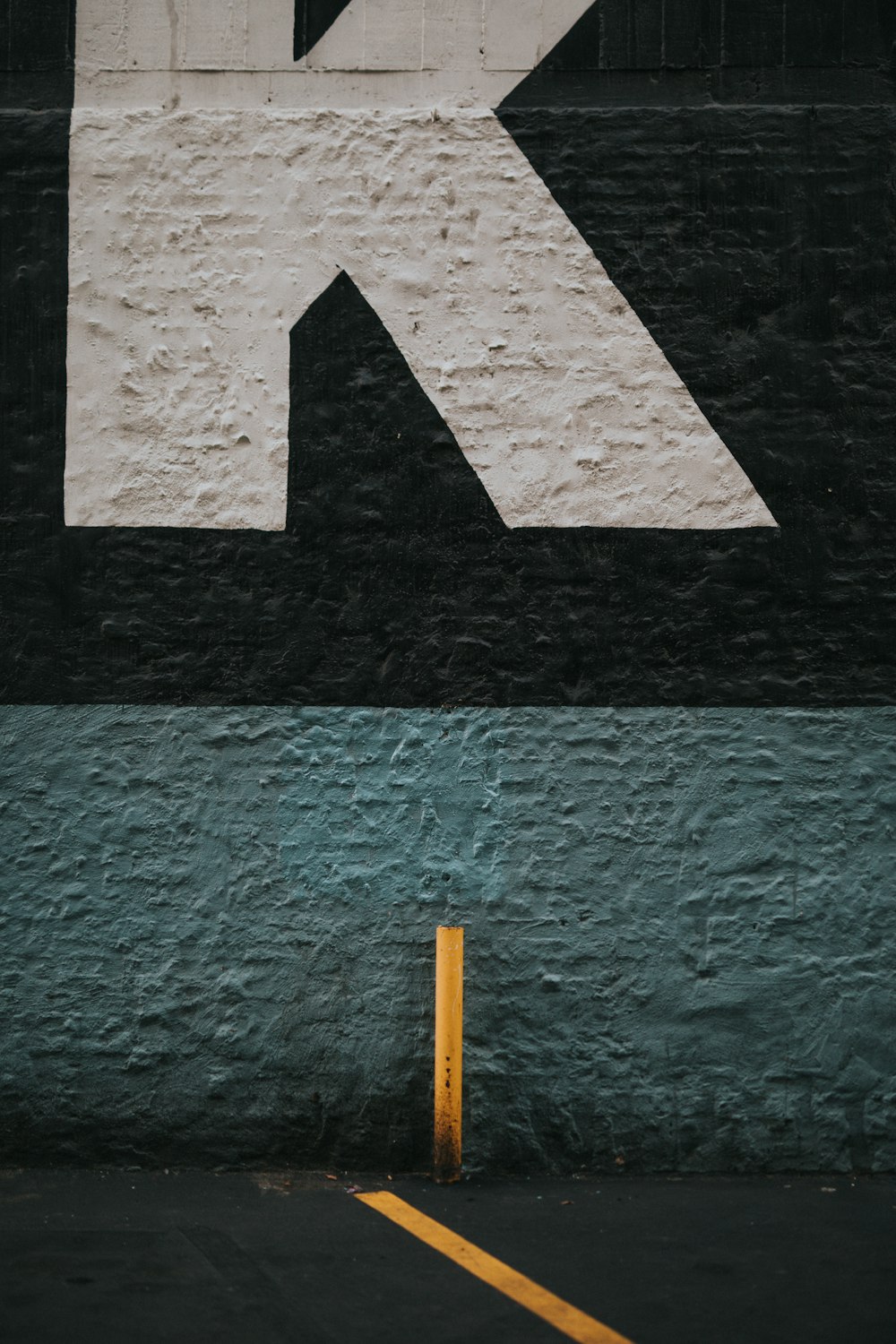 white arrow sign on green concrete wall