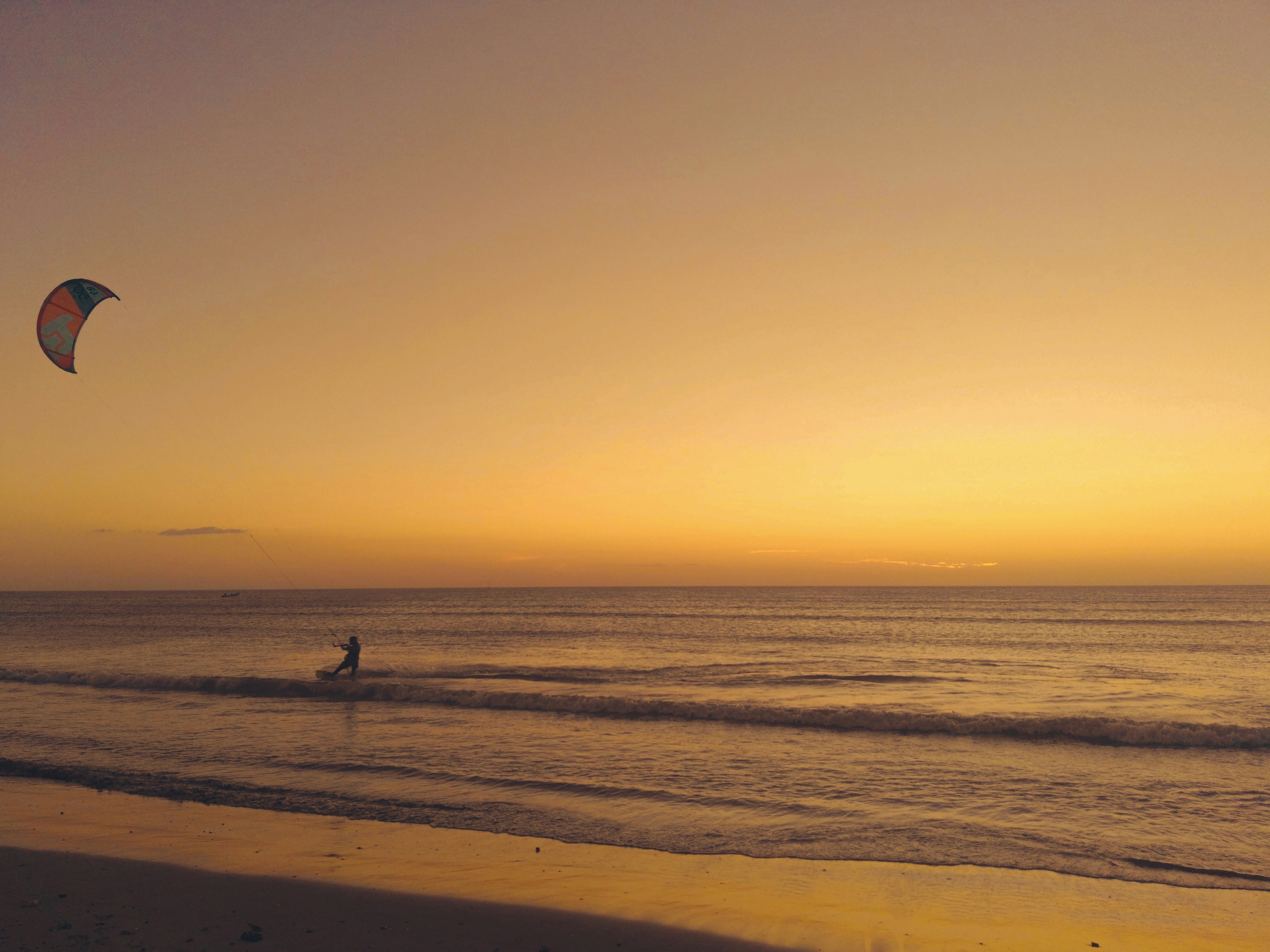person walking on beach during sunset