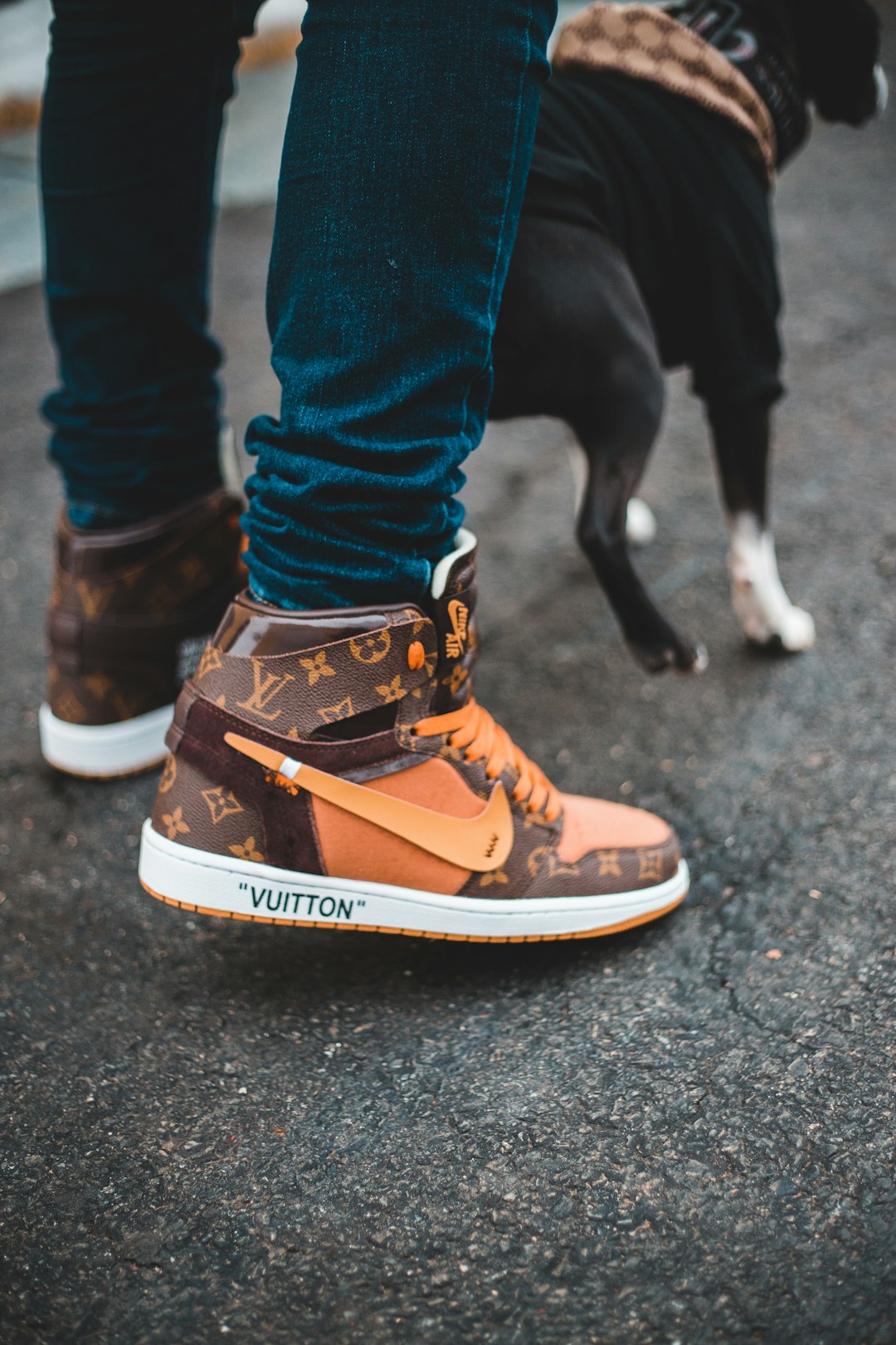 person in blue denim jeans and orange and black nike high top sneakers