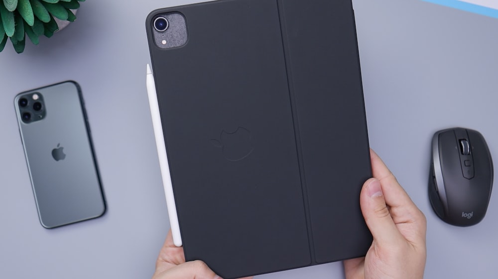 person holding black ipad smart case