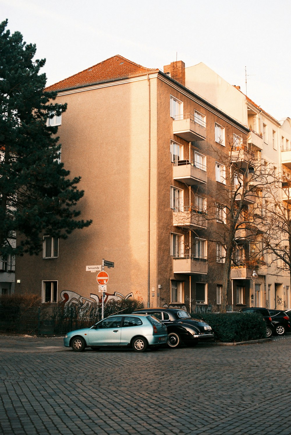 silver sedan parked beside green tree during daytime