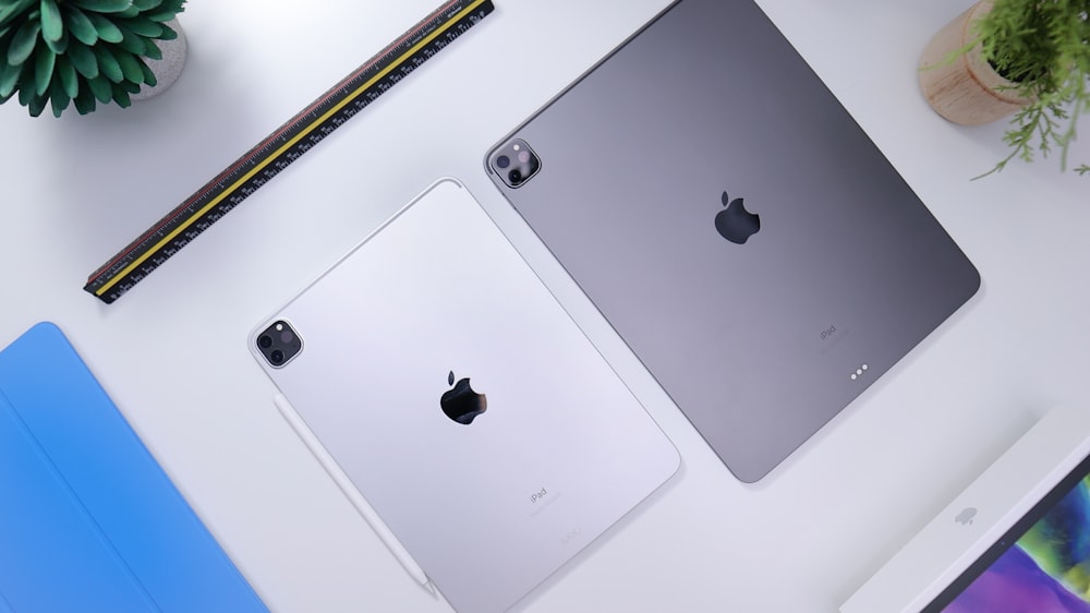 Two refurbished iPads on a white table with plants and ornaments