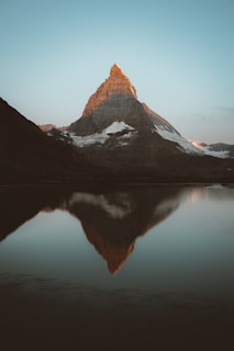 snow covered mountain near lake during daytime