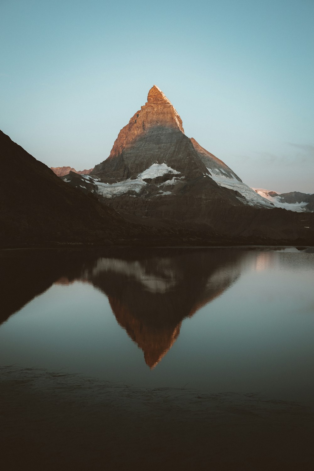 snow covered mountain near lake during daytime