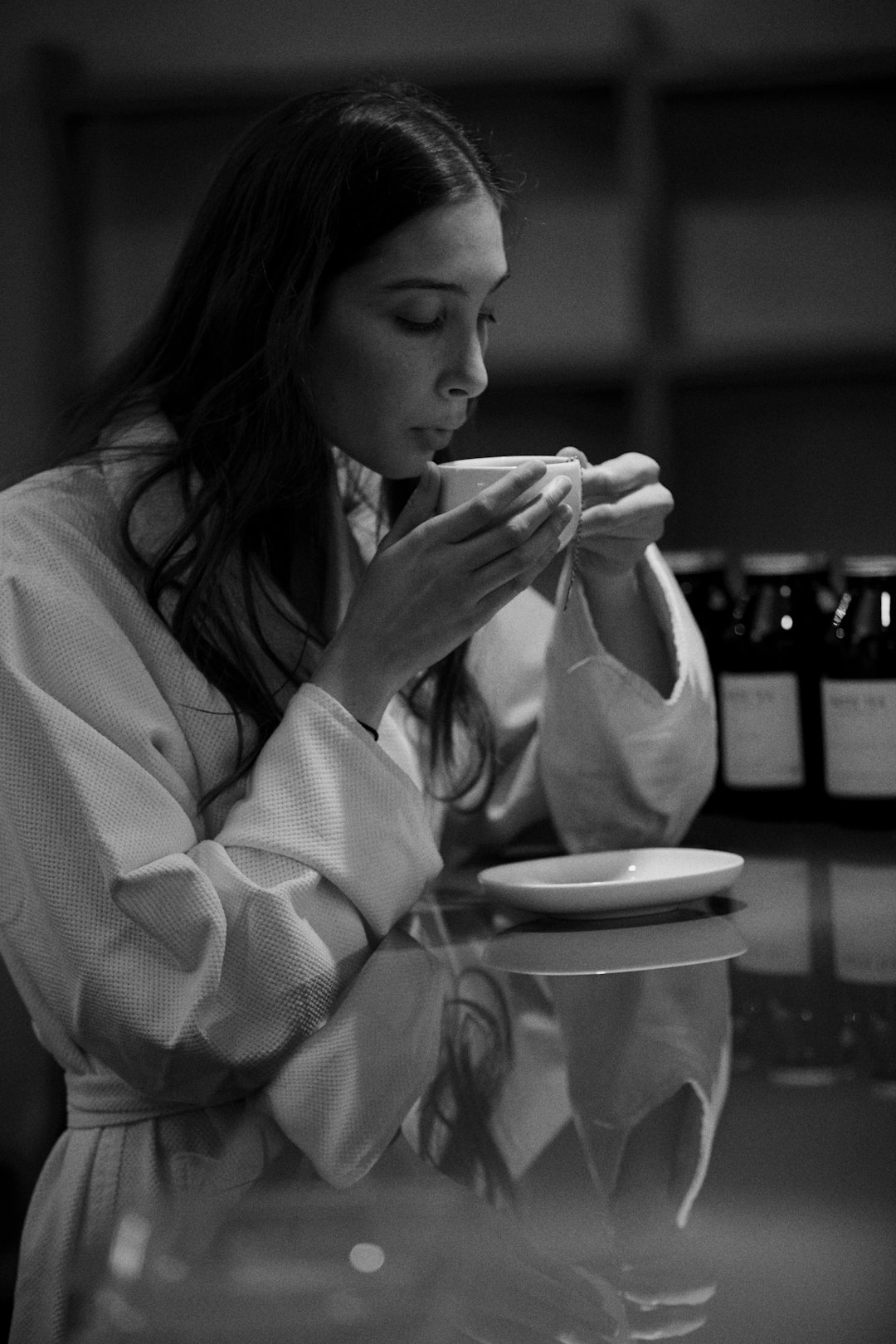 grayscale photo of woman in white robe eating