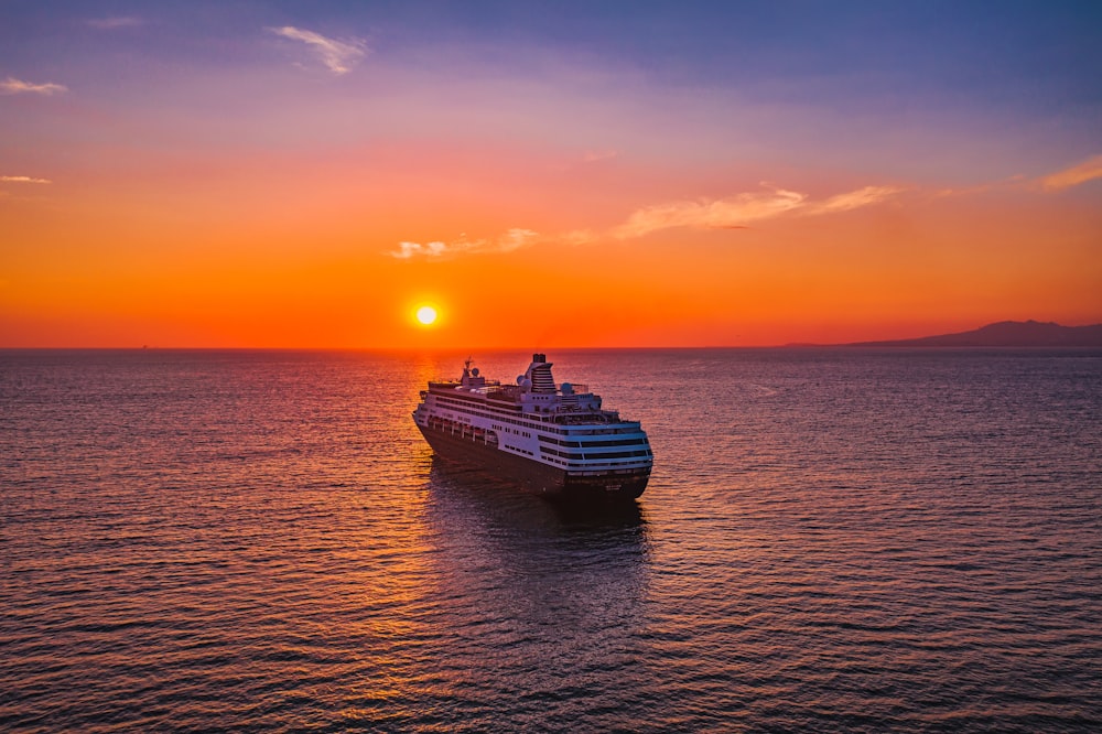 navio branco e preto no mar durante o pôr do sol