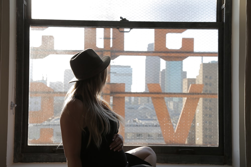 woman in black tank top and black fedora hat sitting on brown wooden bench