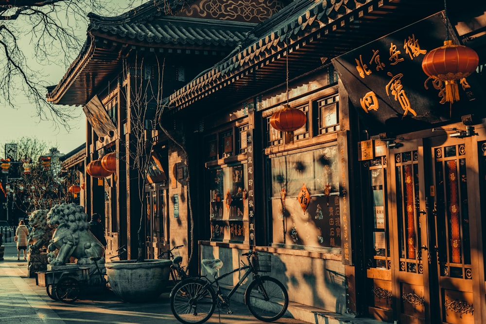 black bicycle parked beside brown wooden building during daytime