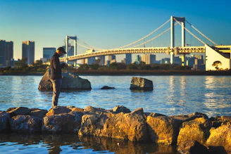 A golden-hour portrait of a person standing on a San Francisco pier with the bay and city skyline glowing behind them.