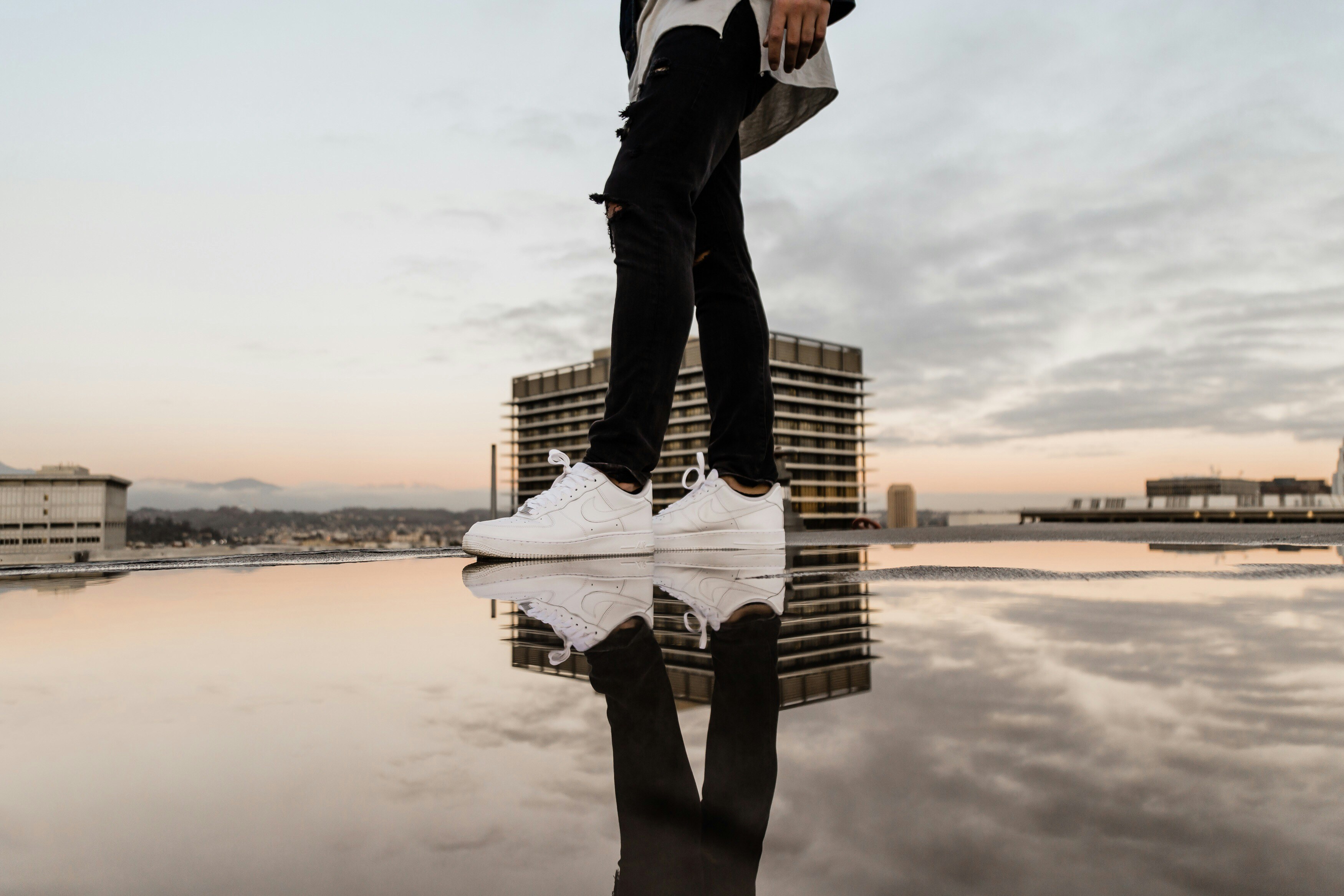 man in black pants and white shirt standing on brown wooden dock during daytime