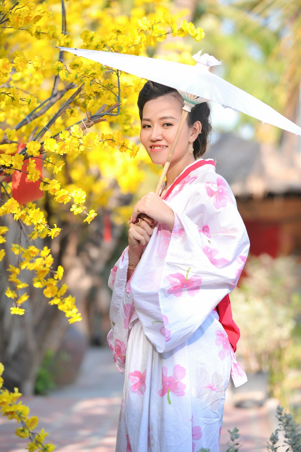 girl in pink kimono standing and holding yellow flowers during daytime