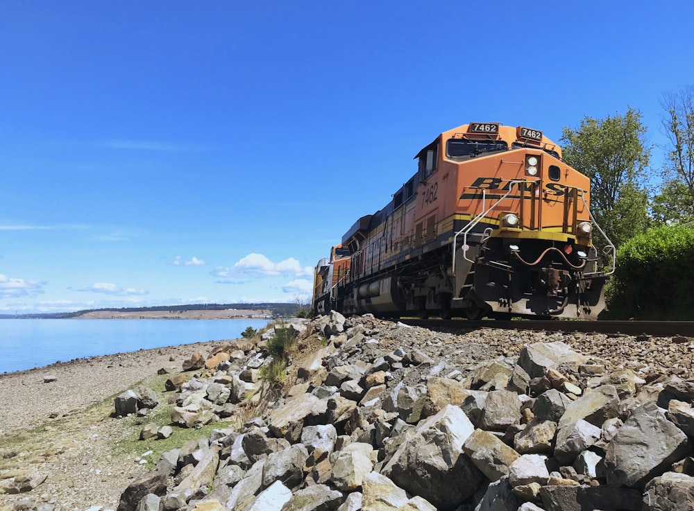 orange train on rocky shore during daytime