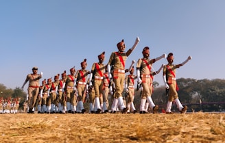 group of people in red and white shirts and pants jumping on brown field during daytime