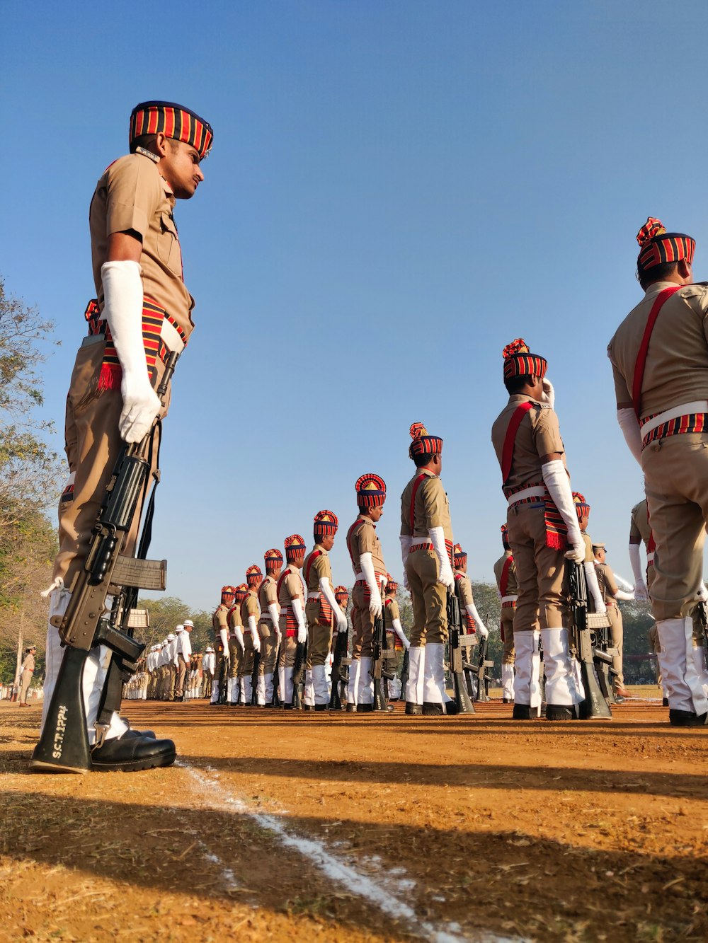 people in brown and white uniform holding airsoft rifle during daytime