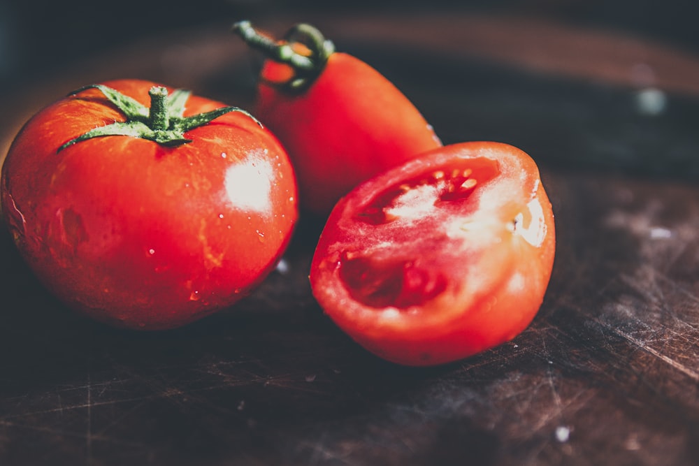 2 pomodori rossi su tavolo di legno nero