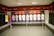 A locker room featuring a row of football jerseys hanging in open lockers. Each jersey is neatly displayed, with names and numbers visible. The room has a modern design with benches in front of the lockers. A mannequin is dressed in a goalkeeper uniform on the left, and a glass case on the right holds a football. The color theme includes red, white, and black accents.