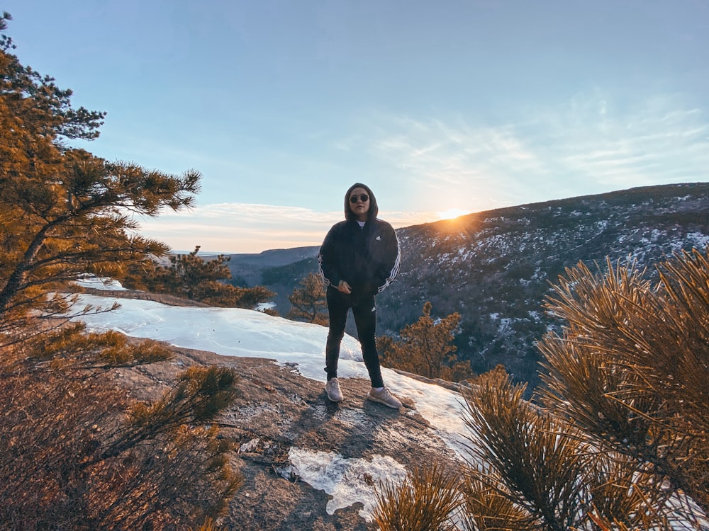 woman in black coat standing on brown rock during daytime