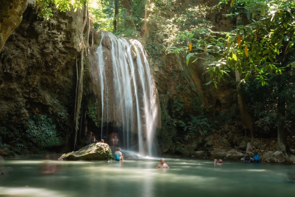 people swimming in the waterfalls during daytime