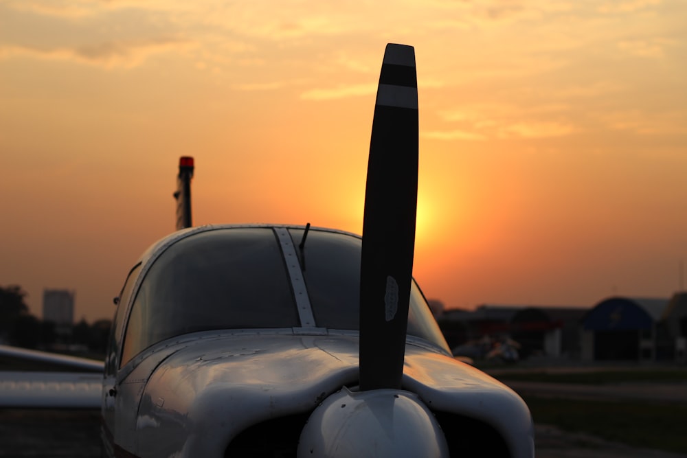 avion blanc et noir sous un ciel orange au coucher du soleil