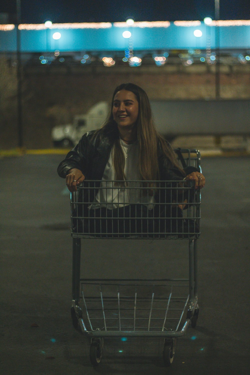 woman in black leather jacket sitting on shopping cart