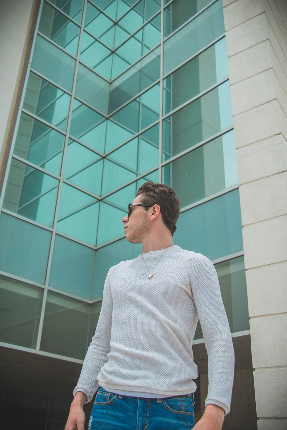 woman in white long sleeve shirt standing in front of teal concrete building during daytime