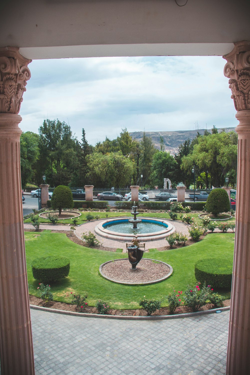 brown concrete outdoor fountain surrounded by green grass and trees during daytime