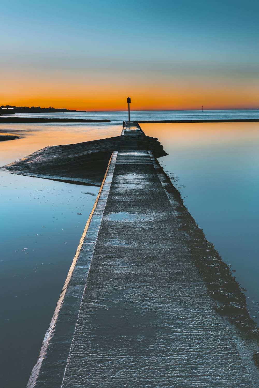 Graues Betondock am Gewässer bei Sonnenuntergang