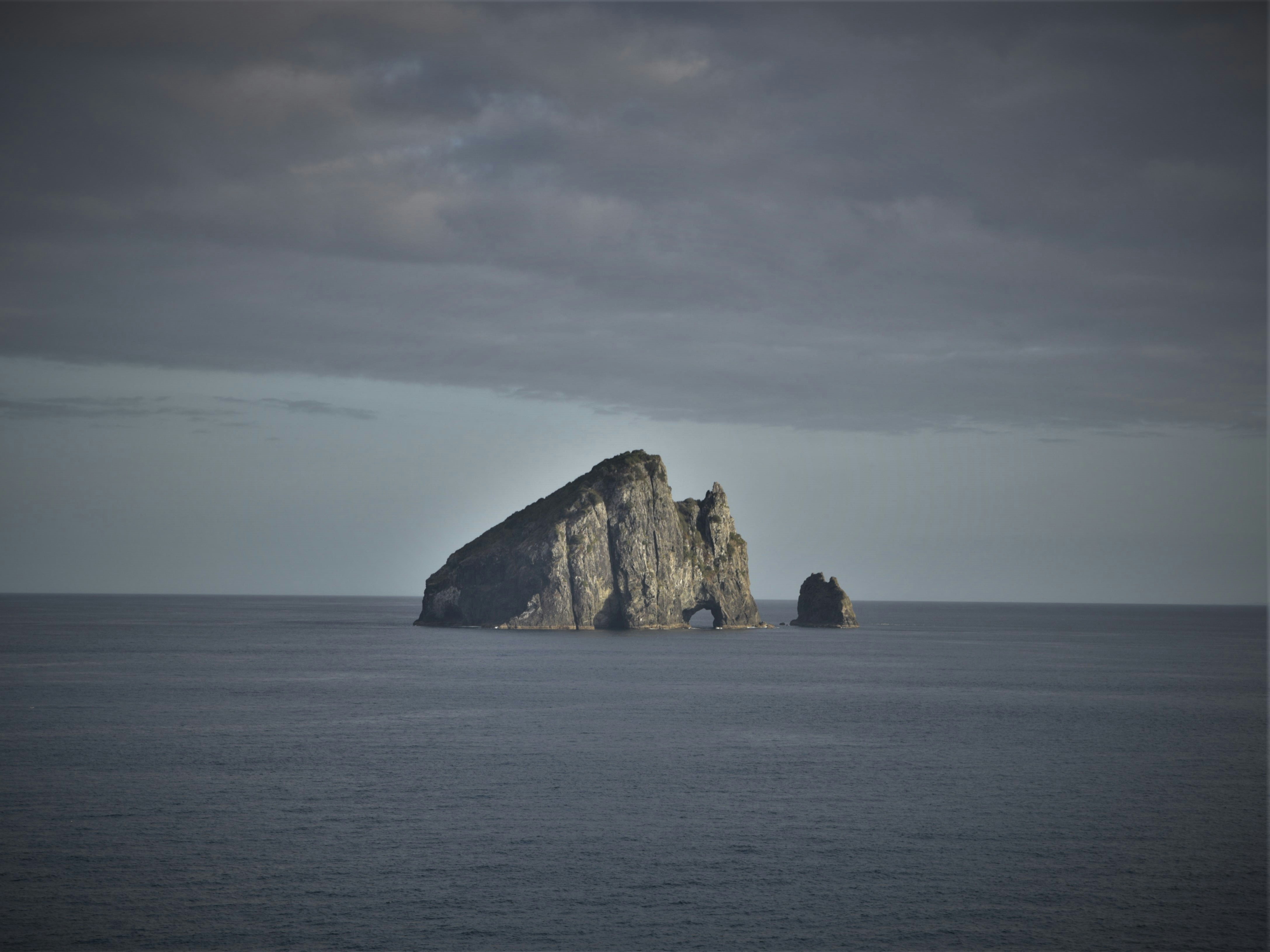 brown rock formation on sea under white clouds during daytime, 