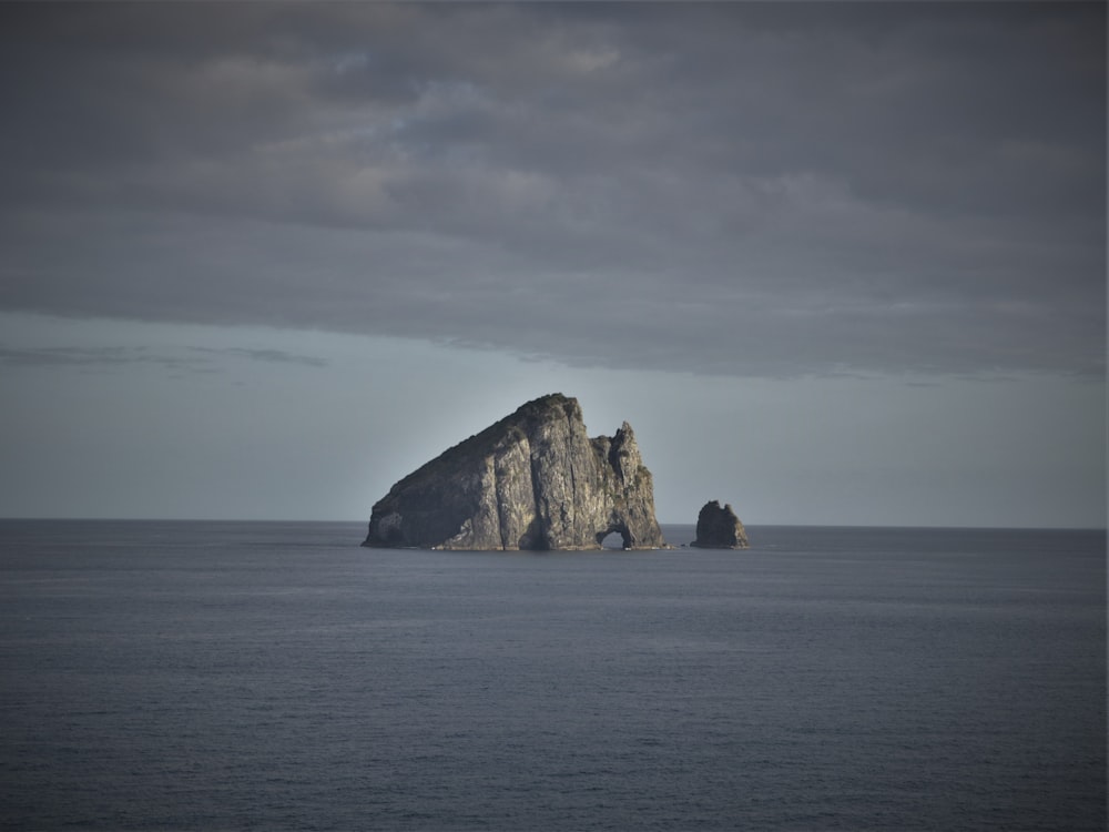 brown rock formation on sea under white clouds during daytime