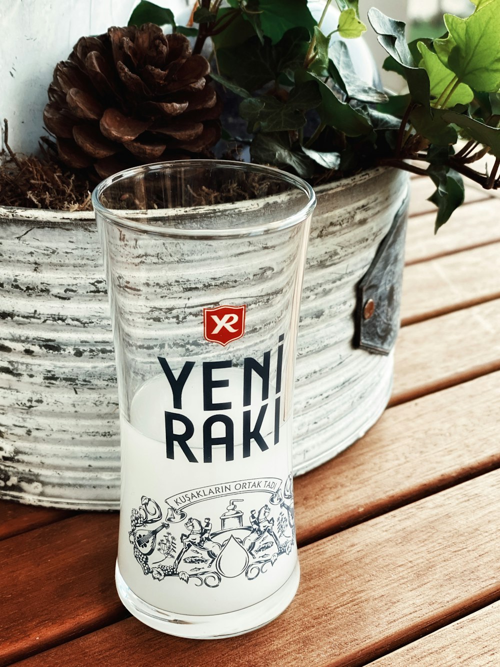 a glass sitting on top of a wooden table next to a potted plant