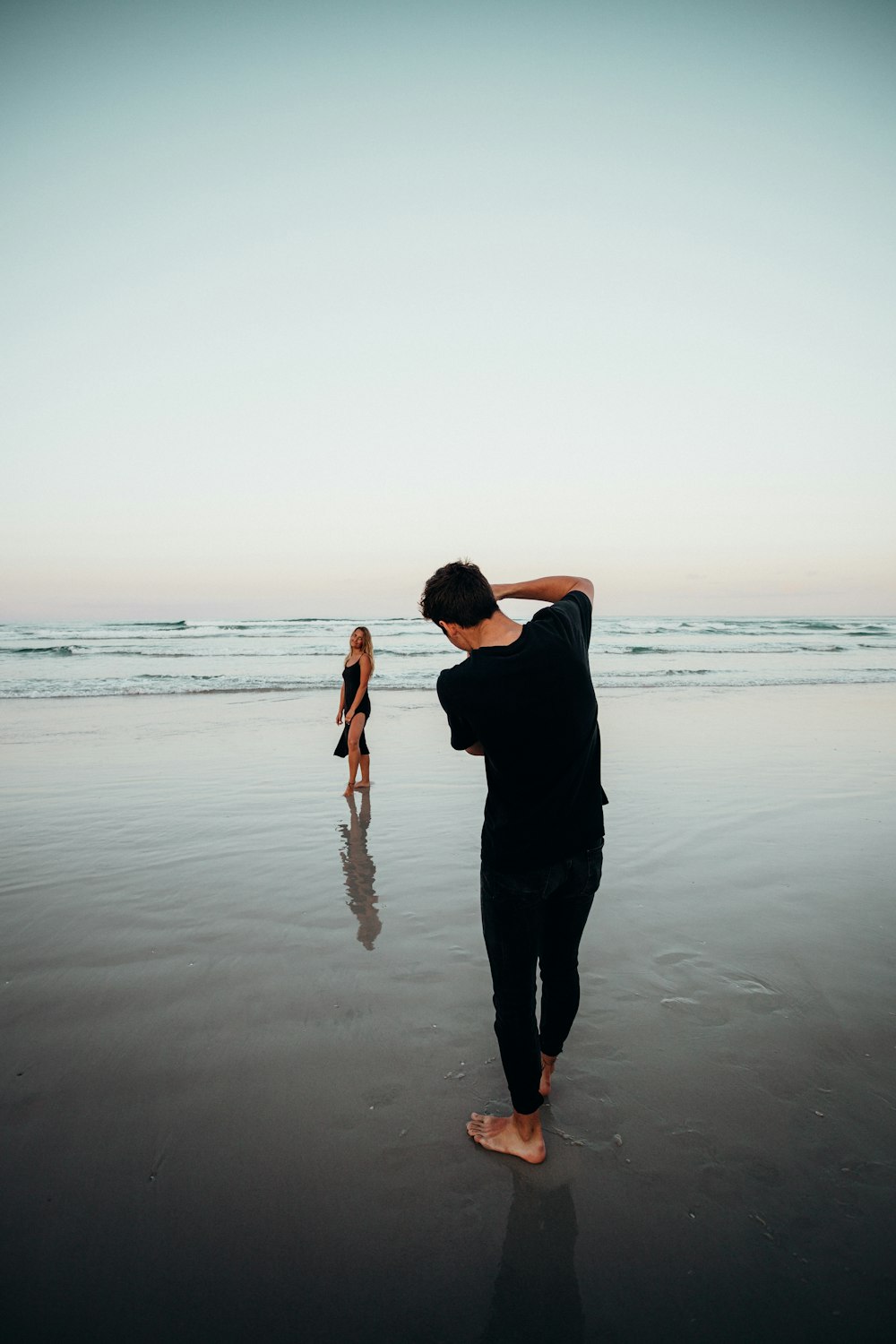 man in black shirt and pants standing on seashore during sunset