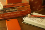 Artfully arranged custom mugs and notebooks with bold orange and royal blue designs on a wooden table.