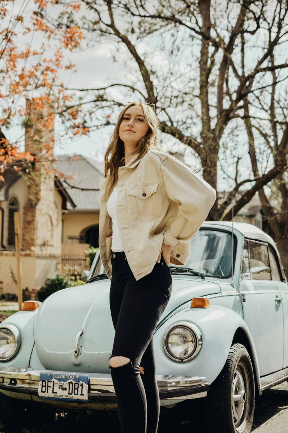 woman in beige coat and black pants sitting on white car