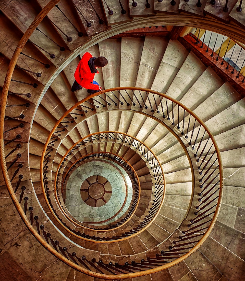 person in red jacket and blue denim jeans standing on spiral staircase