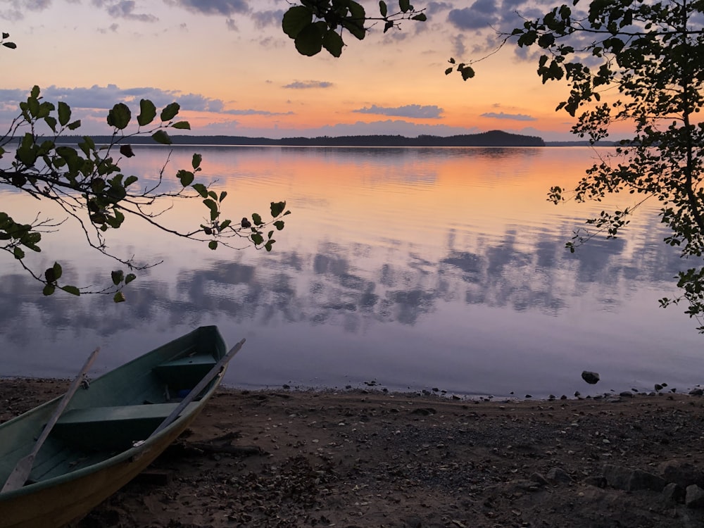 white boat on shore during sunset