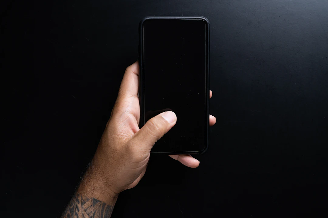 A hand holding a phone against a dark background