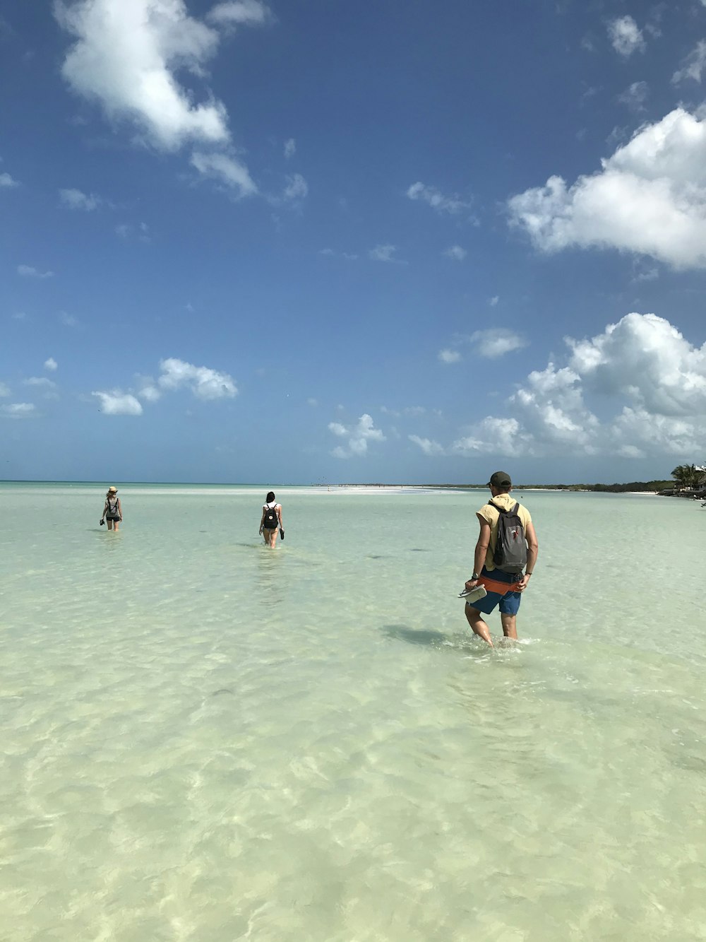 2 women in blue and black swimsuit walking on beach during daytime