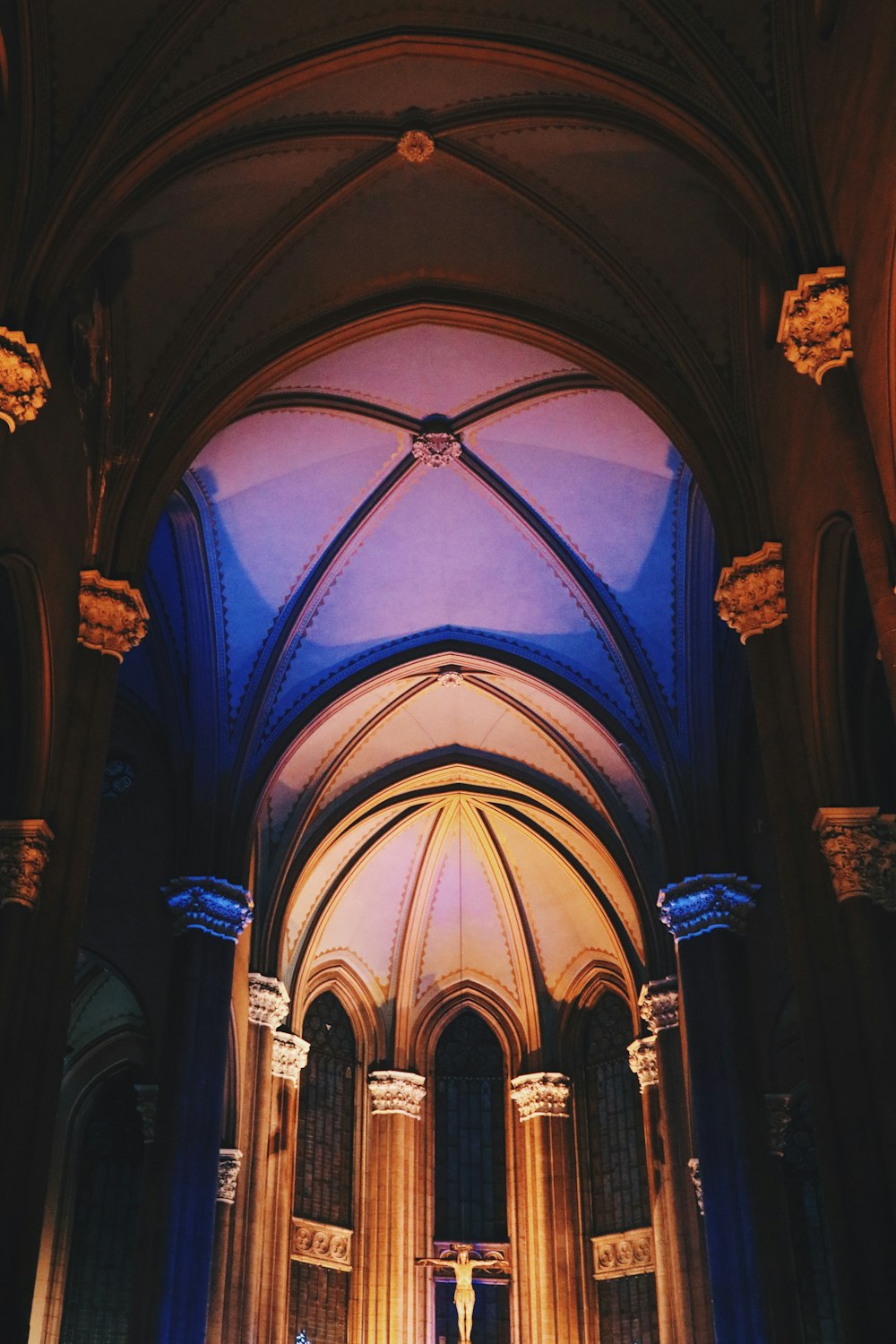 man in black robe standing inside blue and brown cathedral