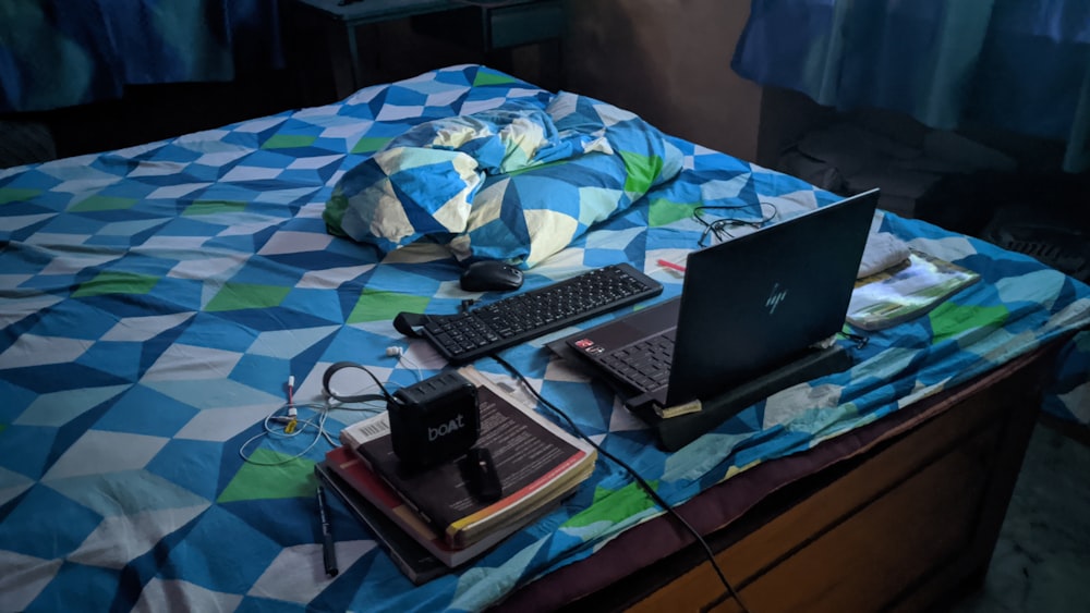 black laptop computer on blue and white bed linen