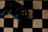 A black gaming controller with colorful buttons labeled X, Y, A, and B is placed on a wooden chessboard.