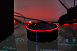 A compact smart home device glowing gently in a modern living room setting.