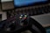 A video game controller with colorful buttons, including green, red, yellow, and blue, placed in front of a blurred laptop keyboard. The focus is on the controller with the surroundings slightly out of focus, indicating a casual gaming setup.