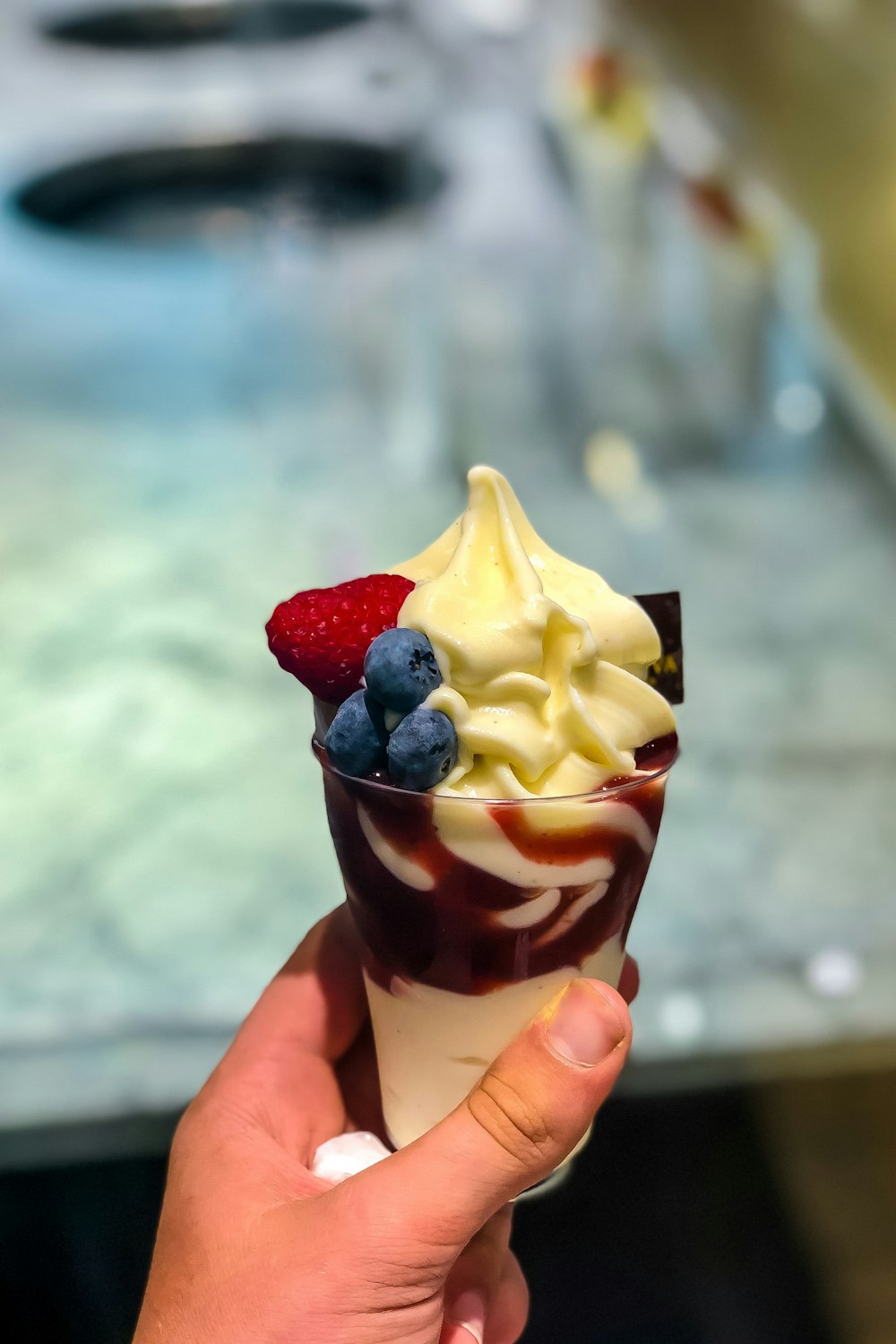 person holding ice cream cone with strawberry and chocolate ice cream