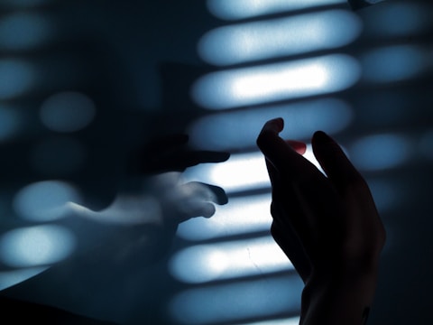 persons hand on white window blinds