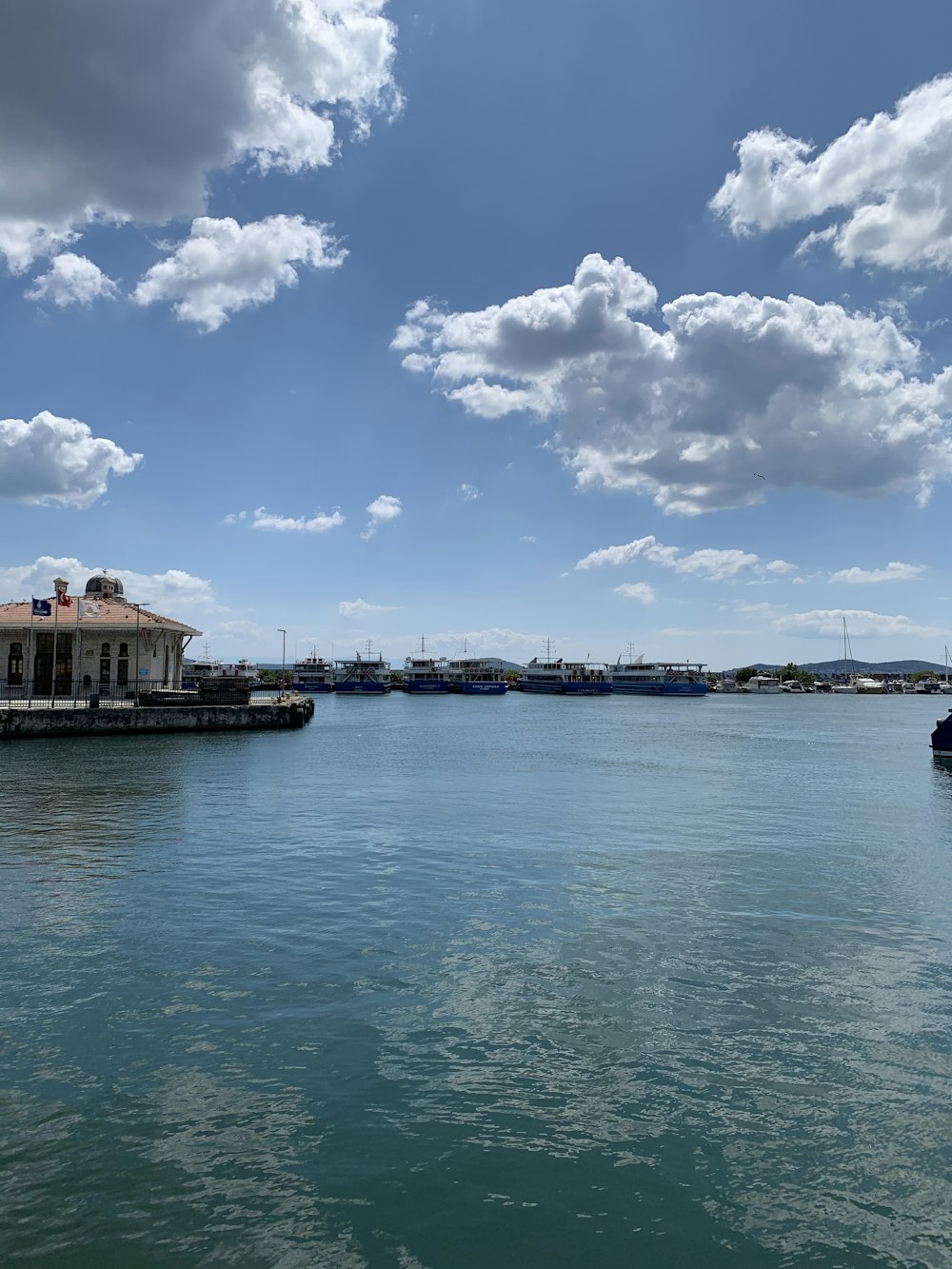 white and brown concrete building near body of water under blue sky and white clouds during