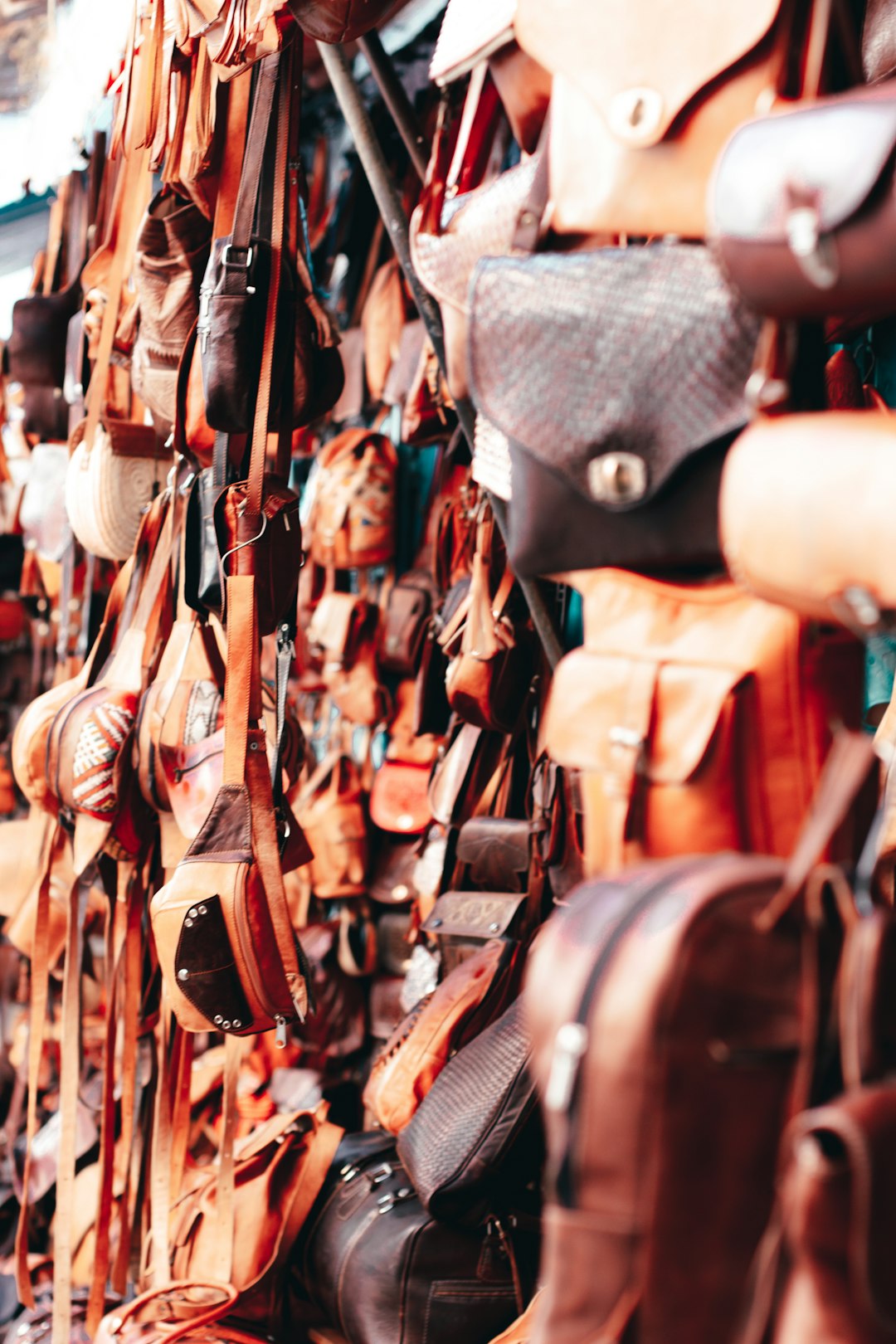 brown leather shoulder bags hanged on brown wooden rack